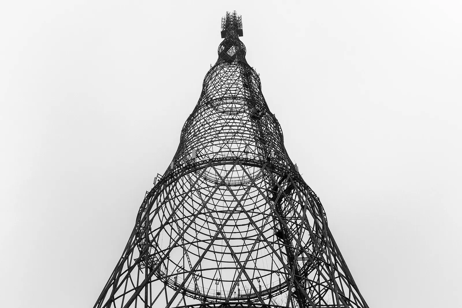 A lattice steel tower of several tiers in winter, above snowy trees and rooftops.